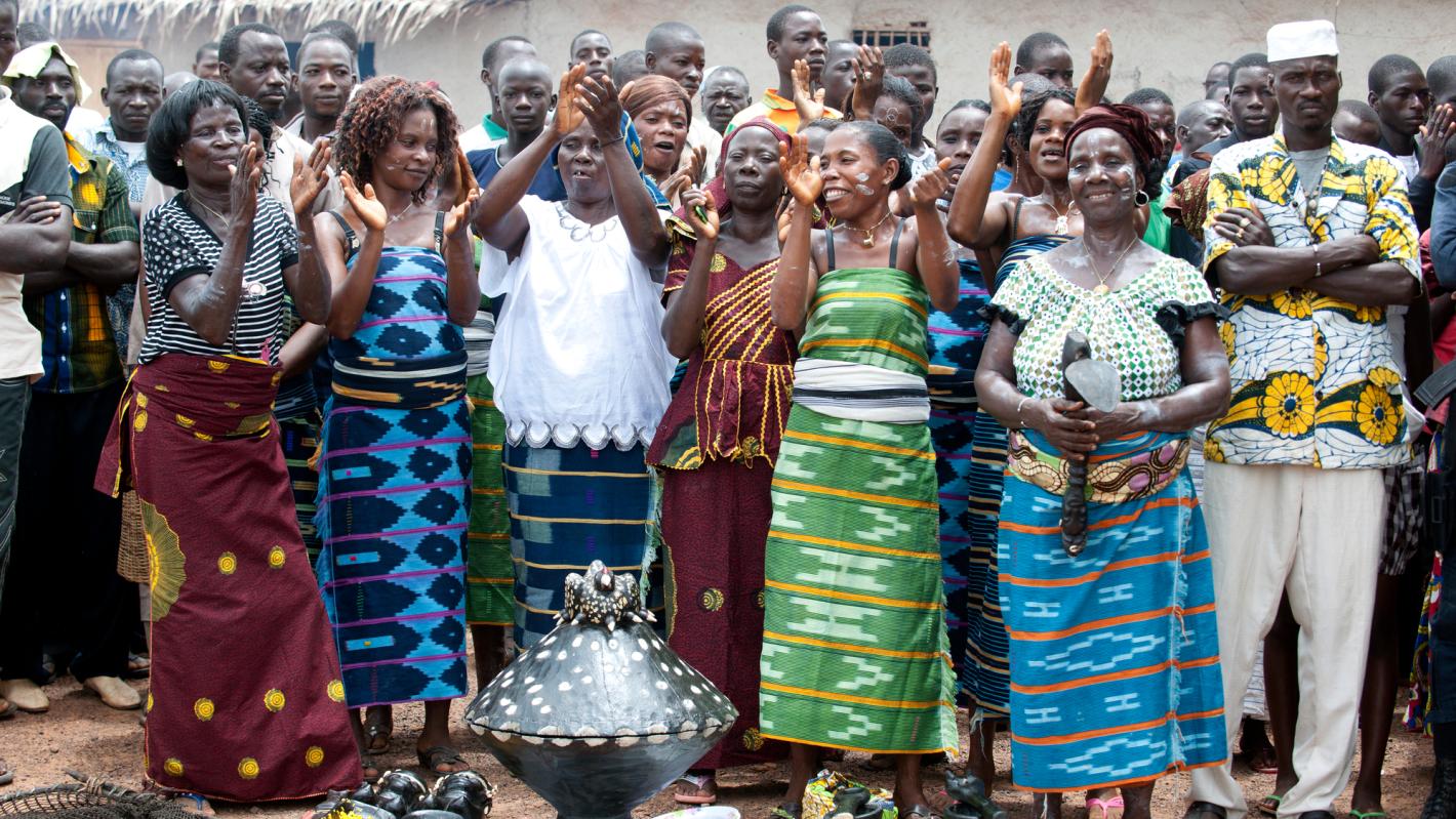A group of people standing in front of some traditional items wearing traditional clothing