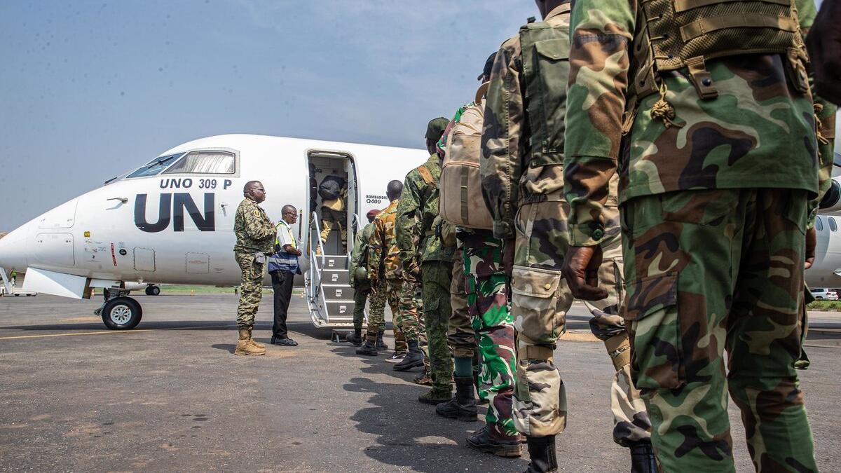 Des Casques bleus font la queue pour monter à bord d’un avion de l’ONU.