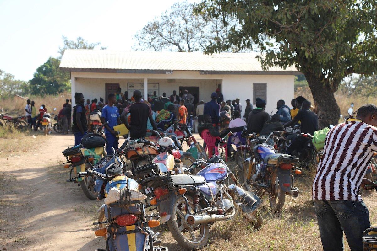 Un groupe de personnes et leurs motos sont photographiés devant un bâtiment.